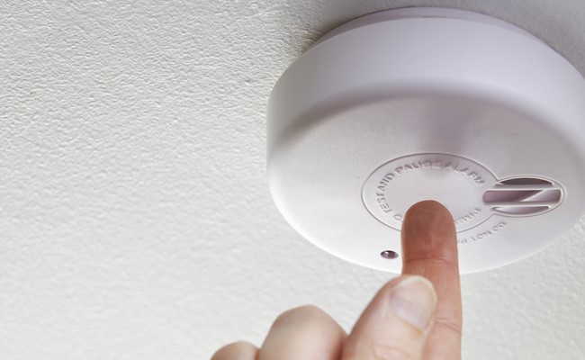 Pressing a smoke alarm reset button