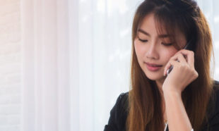 Photo of attractive business woman holding smartphone and sitting at workplace for contact with customer in office.