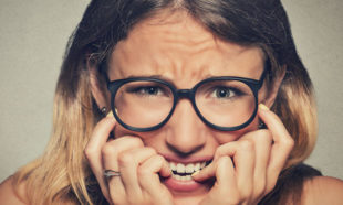 stressed anxious woman in glasses biting fingernails