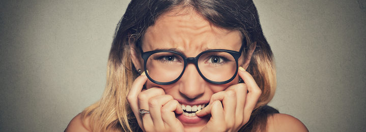 stressed anxious woman in glasses biting fingernails