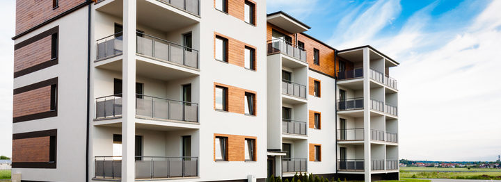 New multi-family block with balconies, bright facade and wooden panels.
