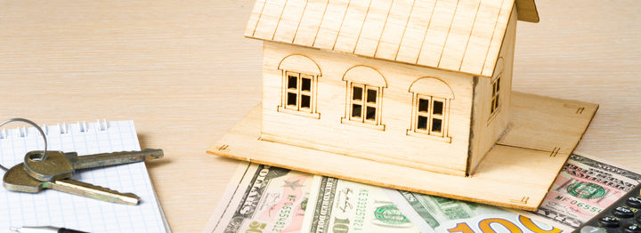 Home savings, budget concept. Model house, pen, calculator and coins on wooden office desk table