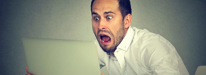 shocked man with laptop computer sitting at table