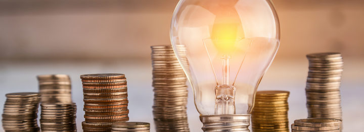 glowing light bulb among many coins