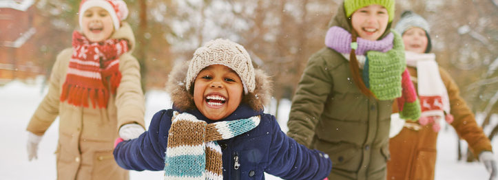 Happy girl holding her friends by hands in snowfall