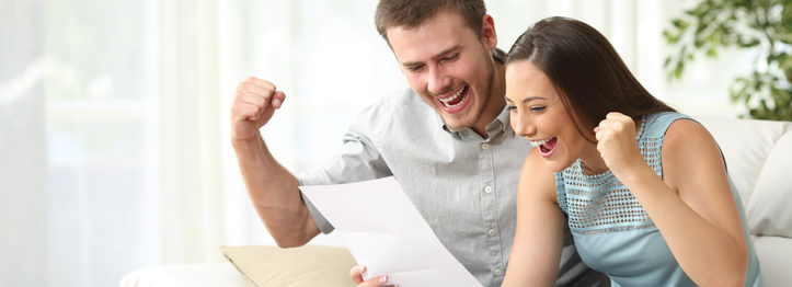 Excited couple reading a letter at home