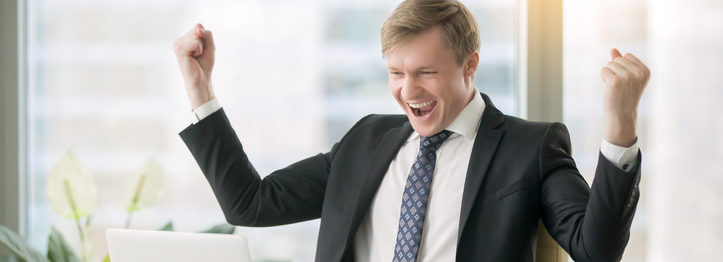 Young happy businessman at the desk