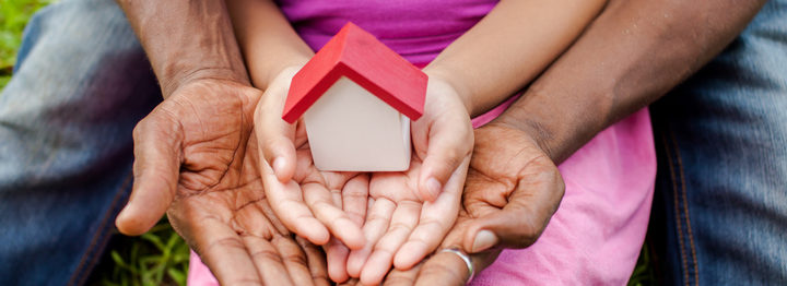 Hands of family together holding house in green park