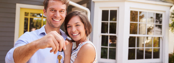 Couple With Keys Standing Outside New Home