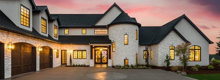 Stunning luxury home with stonework and a three car garage, exterior at sunset
