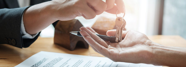 estate agent giving house keys to man and sign agreement in office