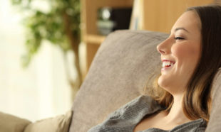Side view portrait of a casual girl relaxing sitting on a sofa in the living room at home