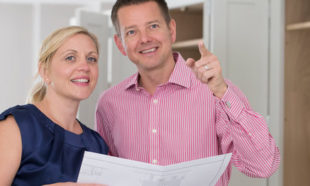 Mature Couple Looking At Plans For New Luxury Kitchen