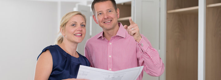 Mature Couple Looking At Plans For New Luxury Kitchen