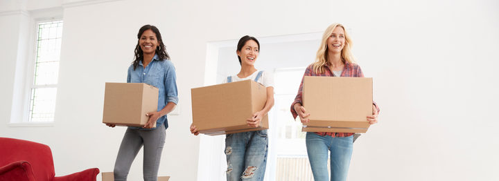 Three Female Friends Carrying Boxes Into New Home On Moving Day