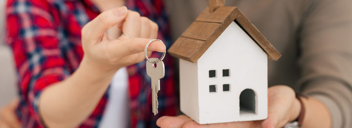 Proud young asian couple with keys and wooden house modelling