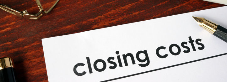 Paper with words closing costs on a wooden background.