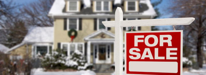Home For Sale Real Estate Sign in Front of Beautiful New House in the Snow.